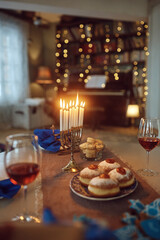 Hanukkah table setting with lit candles in menorah at home.