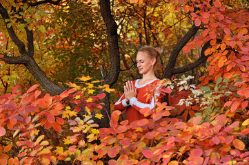 Beautiful woman meditating in the autumn bush