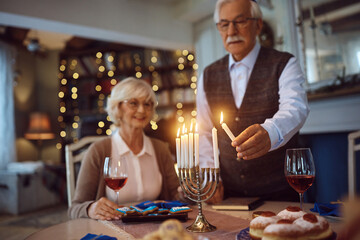 Close up of senior man lighting menorah candles for Hanukkah.