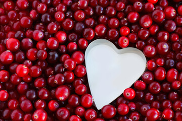 background of ripe cranberries in the shape of a metal heart. Cranberry texture close-up. autumn berry picking