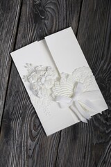 Homemade greeting card in white. With decorative elements. Ribbons, flowers and leaves are attached to cardboard. Close-up.