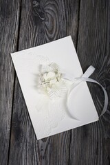 Homemade greeting card in white. With decorative elements. Ribbons, flowers and leaves are attached to cardboard. Close-up.