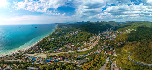 a small resort village of Shepsi on the Black Sea coast near the mountains of the Caucasus covered with green forest - aerial panorama on a sunny summer day