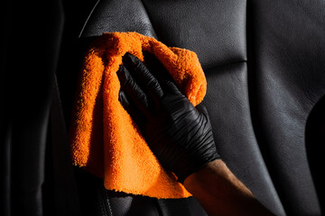 Hand car interior drying of leather seat using microfiber in detailing auto service. Cleaner worker...