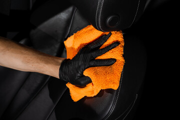 Hand car interior drying of leather seat using microfiber in detailing auto service. Cleaner worker...