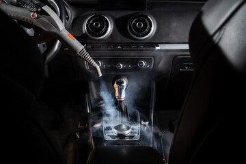 Steam cleaning of gearbox and dashboard in car. Vaping steam. Cleaning individual elements of black...