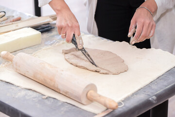 The sculptor sculpts a figurine out of clay with his hands. Creative workflow. Master of his craft. Sculptor's workshop.