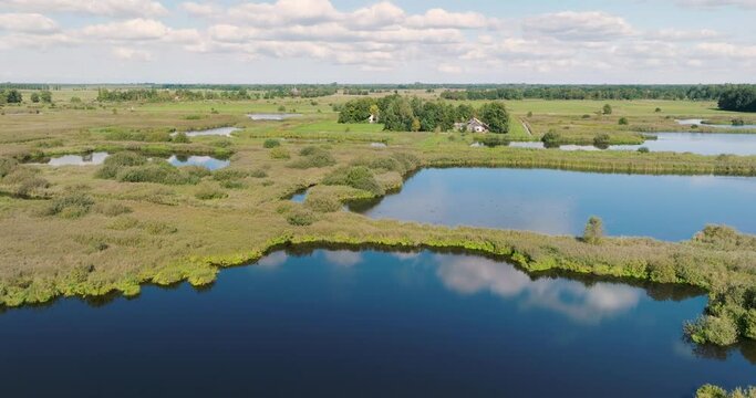 Aerial ascending view of reedland, bushes and lakes with reflection of the sky in national park De Alde Feanen, Earnewald, Friesland, Netherlands