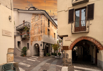 Cuneo, Piedmont, Italy - October 14, 2022: Contrada Mondovì, ancient street in the historic center with frescoed medieval buildings at sunset