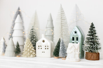 Modern christmas scene, miniature snowy village on white table. Merry Christmas! Stylish little...