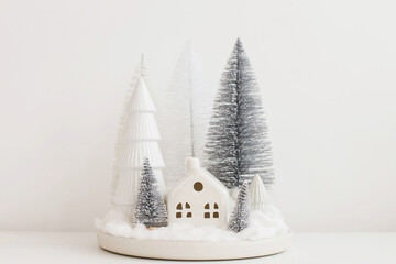 Winter hygge, cozy christmas scene, miniature snowy village on white table. Merry Christmas!...