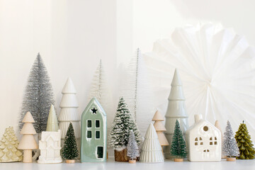 Modern christmas scene, miniature snowy village on white table. Merry Christmas! Stylish little...