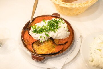 Eggplant in tomato sauce and feta cheese. Greek dish in a pan in Athens