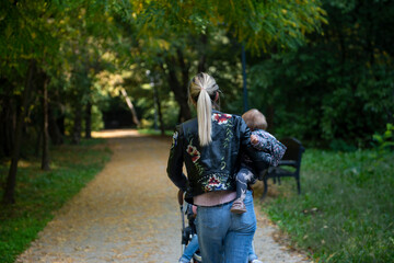 A mother holds her daughter in her arms while walking through the park