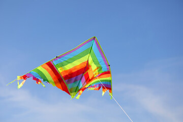 kite with stripes of various colors of the rainbow flying