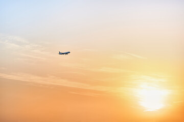 Fototapeta na wymiar Airplane landing in the rays of the setting sun. Airplane flight on summer vacation.