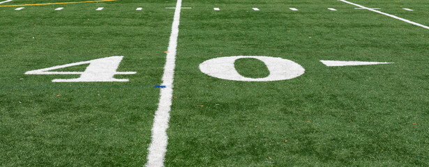 Obraz premium Green synthetic turf field on a clear autumn day with a shallow depth of field and copy space