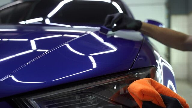 Hand applying of nano ceramic protective coat to protect car from scratches. 4k video process of apply ceramic layer on body car using sponge close-up in detailing auto service.