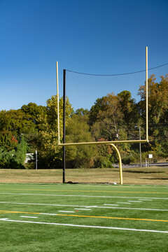 Green synthetic turf field with goal posts on a clear autumn day with a shallow depth of field and copy space