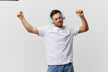 Cheerful tanned handsome man in basic t-shirt headphones listen favorite song dance smile posing isolated on over white studio background. Copy space Banner Mockup. Music Cool playlist concept