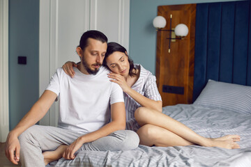 couple in love in white clothes is sitting on the bed in the bedroom in the morning.