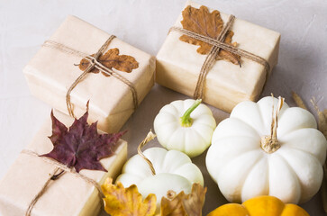 Autumn background. Pumpkins and gifts on a beige background