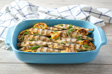 Baked sardines with rosemary and lemon in a blue square baking tray, selective focus.