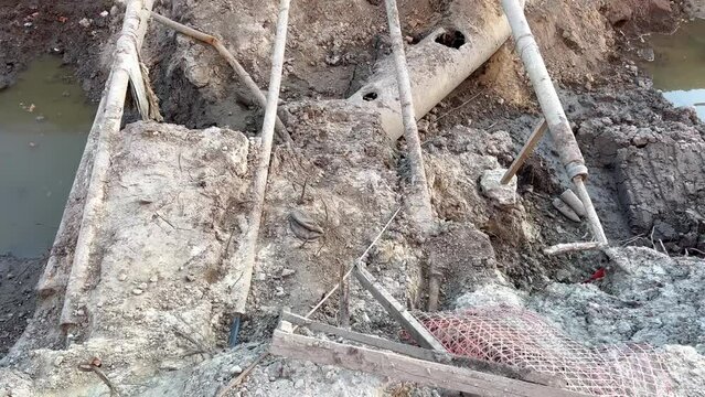 Burst underground sewer pipes, old cracked and damaged sewer pipes. Breakdown of the sewage system. A hole in the ground from an aerial artillery shell. Replacement of old pipes