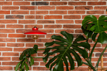 Red lamp on the background of a red brick wall. A potted palm tree near a lamp
