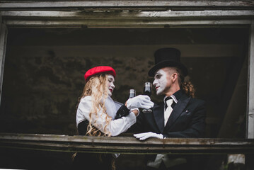 The hatter and alice in wonderland. A girl with long hair in a red hat with white makeup on her...