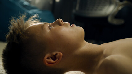 Thoughtful boy lays on the carpetted floor thinks about his soccer match with school sports team. Determined young boy with bare upper body in his room.