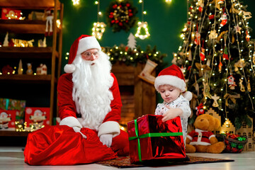 Little boy getting big Christmas gift from Santa Claus. Christmas Scenes. New Year concept 