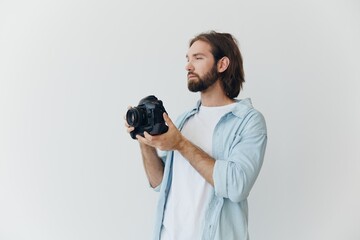 A male hipster photographer in a studio against a white background looks through the camera...