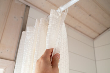 Hand closes a waterproof curtain in the bathroom, which covers the shower and prevents moisture...