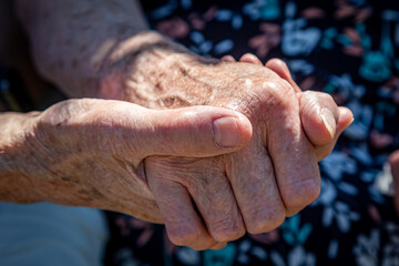 An elderly couple holding hands, with a shallow depth of field