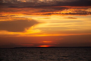Amazing Black sea. Clouds and sand landscape background. Drama contrast sky and red sun. Golden blue hour at the ocean romantic evening. Tropical island summer paradise. Wild rest in camp.
