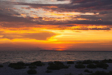 Amazing Black sea. Clouds and sand landscape background. Drama  yellow sky and red sun. Golden blue hour at the ocean romantic evening. Tropical island summer paradise. Wild rest in camp.