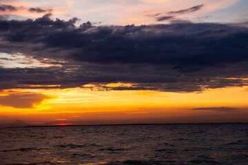 Fototapeta premium Amazing Black sea evening, Clouds landscape background. Drama yellow sky and sun. Golden blue hour at the ocean romantic evening. Tropical island summer paradise. Wild rest robinson tourism in camp.