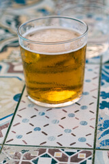 Glass of beer served on a drinking glass on a tiled textured Brick surface