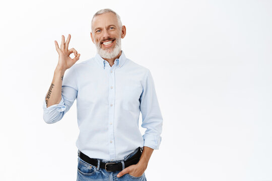 Image of businessman showing okay sign, ok gesture, approve, recommend something awesome, standing against white background