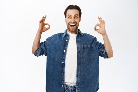 Enthusiastic Bearded Man Shows Okay, Ok Sign, Approve Smth, Recommending Smth Good, Standing In Casual Clothes Over White Background