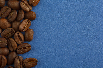 coffee beans are scattered on a blue background from the edge of the frame. Coffee on a blue background