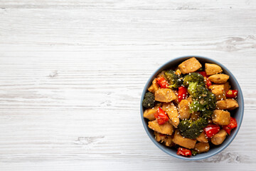 Homemade One-Pan Chicken And Broccoli Stir-Fry in a Bowl on a white wooden background, top view. Flat lay, overhead, from above.