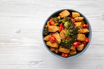 Homemade One-Pan Chicken And Broccoli Stir-Fry in a Bowl on a white wooden background, top view. Flat lay, overhead, from above. Copy space.