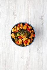 Homemade One-Pan Chicken And Broccoli Stir-Fry in a Bowl on a white wooden background, top view. Flat lay, overhead, from above.