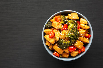 Homemade One-Pan Chicken And Broccoli Stir-Fry in a Bowl on a black background, top view. Flat lay, overhead, from above. Copy space.