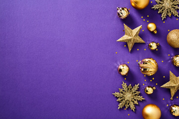 Glitter gold Christmas decorations, baubles, stars, snowflakes, confetti on purple background. Flat lay, top view.