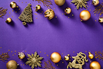 Glitter gold Christmas decorations and baubles on purple background. Flat lay, top view.