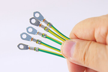 A hand holds colored mounting wires on a white background in close-up.