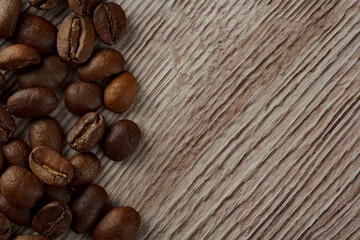 coffee beans are scattered on a wood background from the edge of the frame. Coffee on a wood background